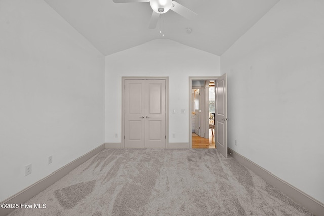 unfurnished bedroom with lofted ceiling, carpet flooring, baseboards, and a closet