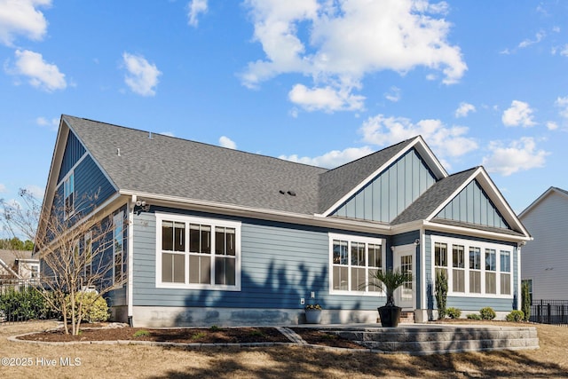 rear view of house with board and batten siding and a shingled roof