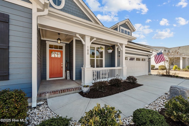 view of exterior entry featuring concrete driveway, a garage, and covered porch