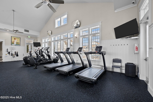 gym with visible vents, high vaulted ceiling, ceiling fan, and wainscoting