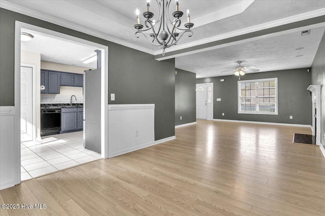 148 Mendover Dr, Jacksonville, NC 28546 - unfurnished living room featuring a sink, ceiling fan, light wood-style flooring, a chandelier, and a raised ceiling