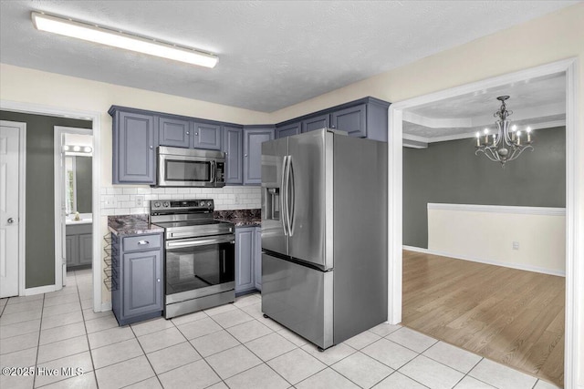 148 Mendover Dr, Jacksonville, NC 28546 - kitchen featuring stainless steel appliances, light tile patterned floors, a chandelier, tasteful backsplash, and a textured ceiling
