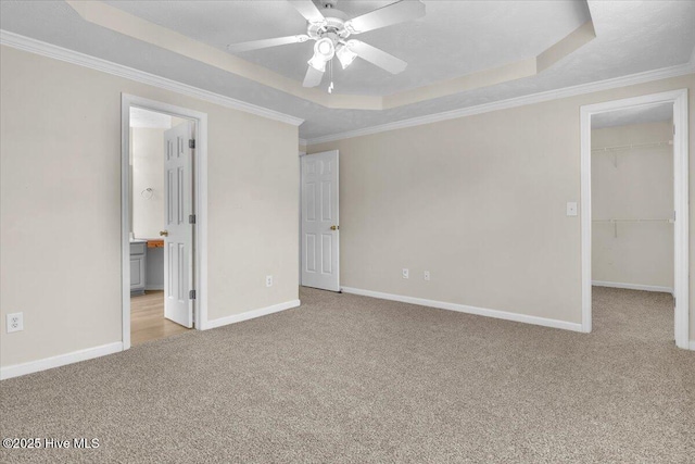 148 Mendover Dr, Jacksonville, NC 28546 - unfurnished bedroom featuring a tray ceiling, carpet, a walk in closet, baseboards, and ornamental molding