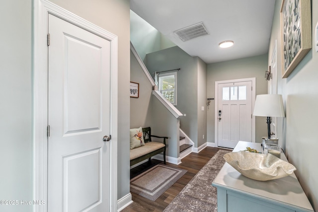 entrance foyer with stairway, baseboards, visible vents, and dark wood-style flooring