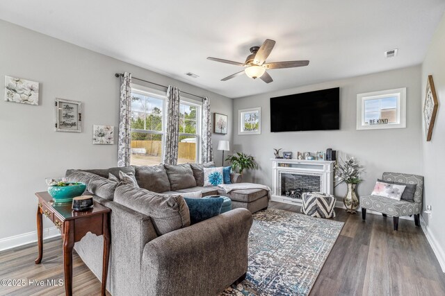 living area featuring a ceiling fan, wood finished floors, visible vents, and baseboards