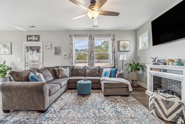 living area featuring a ceiling fan, visible vents, a fireplace, and wood finished floors