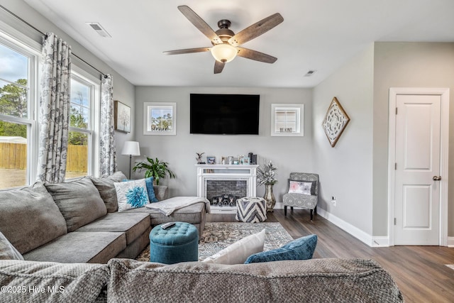 living room with baseboards, visible vents, ceiling fan, wood finished floors, and a fireplace