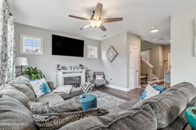 living area featuring a fireplace, wood finished floors, visible vents, baseboards, and stairway