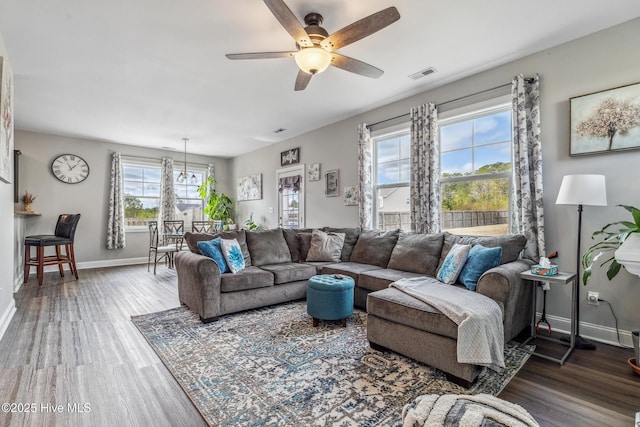 living room with a ceiling fan, wood finished floors, visible vents, and baseboards