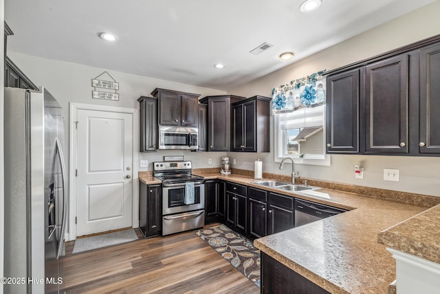 kitchen with recessed lighting, stainless steel appliances, wood finished floors, a sink, and visible vents