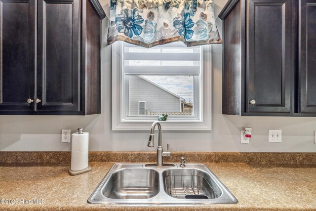 kitchen with dark countertops, a sink, and dark brown cabinetry