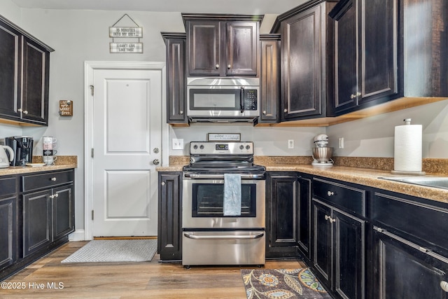 kitchen with appliances with stainless steel finishes, light countertops, and light wood-style floors