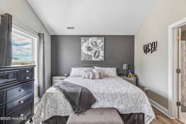 bedroom featuring lofted ceiling, light wood-style flooring, visible vents, and baseboards