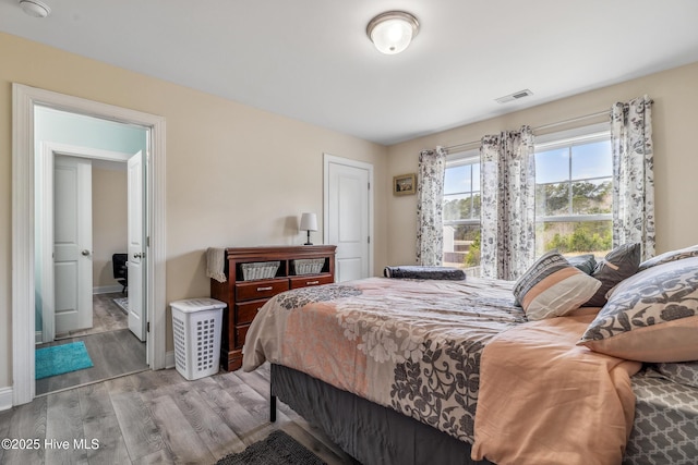 bedroom featuring visible vents, baseboards, and wood finished floors