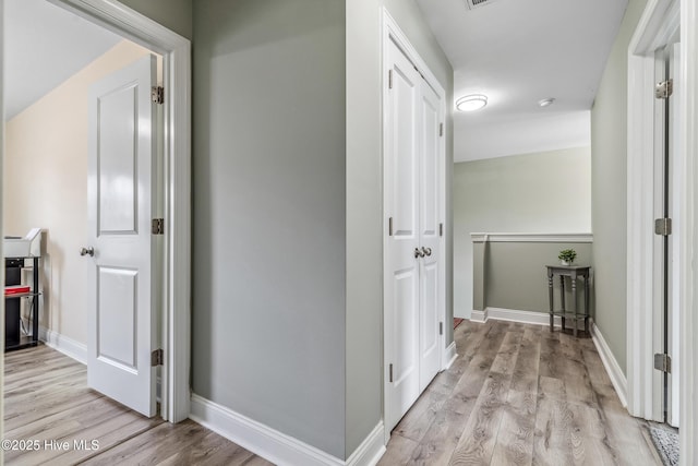 hallway featuring light wood-style floors, visible vents, and baseboards