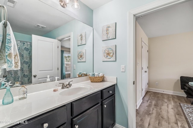 full bath with vanity, wood finished floors, visible vents, and baseboards