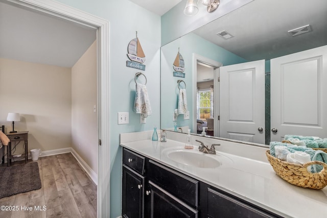 bathroom featuring vanity, wood finished floors, visible vents, and baseboards