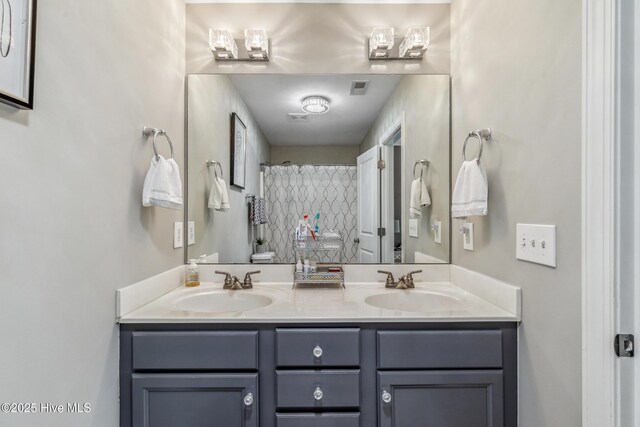 bathroom with double vanity, a sink, and visible vents