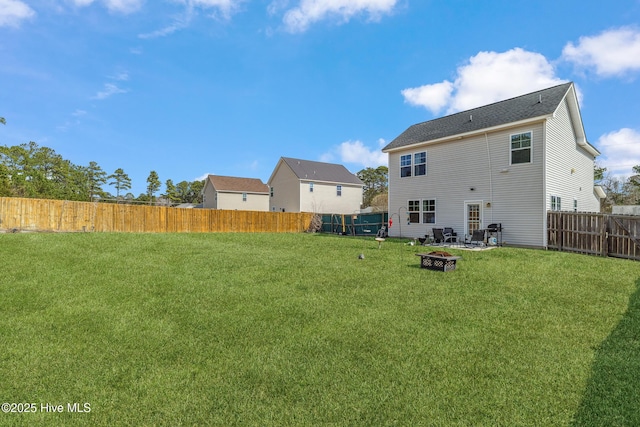 rear view of property featuring an outdoor fire pit, a fenced backyard, and a lawn