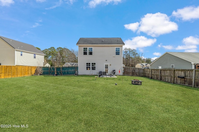 rear view of house with an outdoor fire pit, a fenced backyard, and a lawn