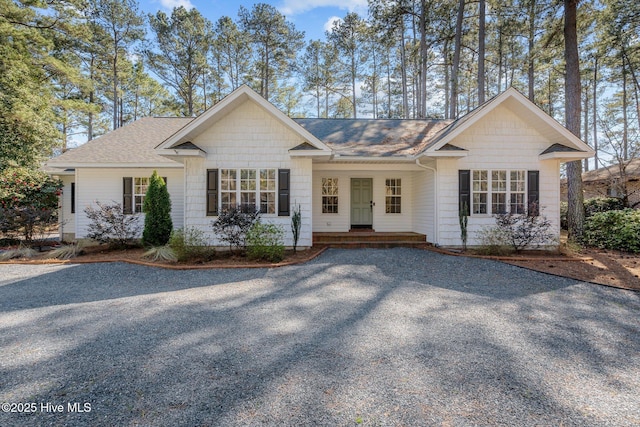 ranch-style house featuring gravel driveway and a shingled roof