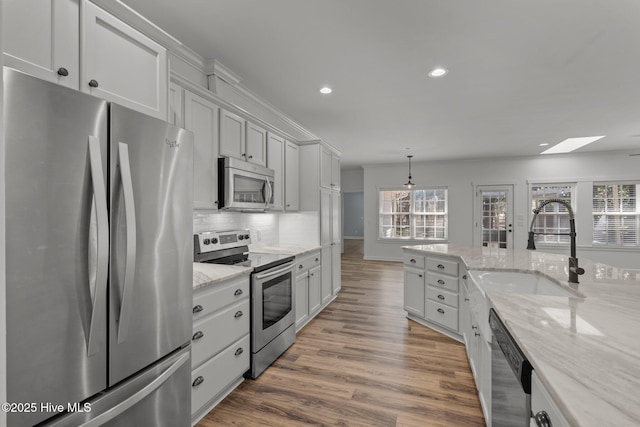 kitchen with recessed lighting, stainless steel appliances, wood finished floors, a sink, and decorative backsplash