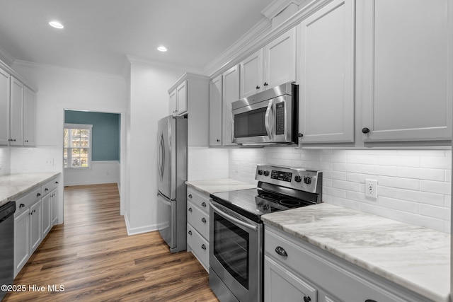 kitchen with baseboards, wood finished floors, light stone countertops, stainless steel appliances, and crown molding