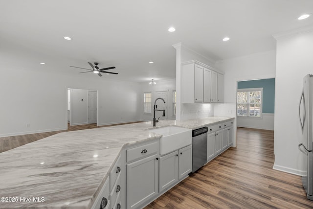 kitchen with appliances with stainless steel finishes, ornamental molding, wood finished floors, a peninsula, and a sink