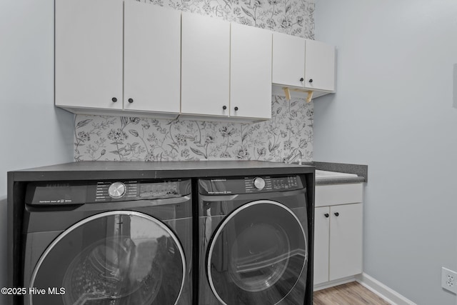 clothes washing area featuring cabinet space, light wood-style flooring, baseboards, and washer and clothes dryer