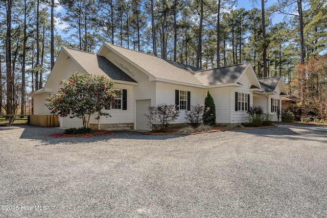 view of side of property featuring a garage, roof with shingles, and driveway