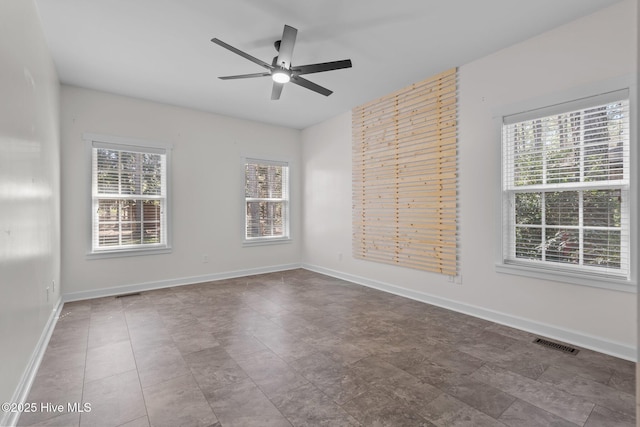 unfurnished room with a ceiling fan, visible vents, and baseboards