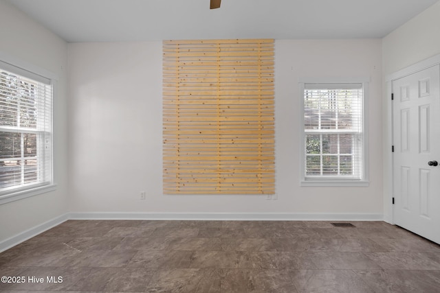 spare room featuring plenty of natural light, visible vents, and baseboards