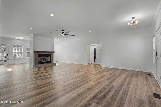 unfurnished living room featuring crown molding, baseboards, a fireplace with raised hearth, and wood finished floors