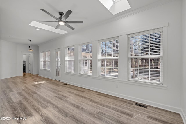 interior space featuring ornamental molding, a skylight, visible vents, and baseboards