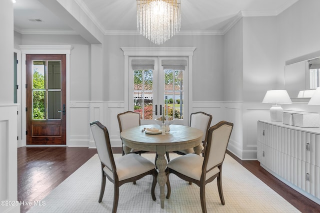 2900 Legends Dr, Southport, NC 28461 - dining space featuring plenty of natural light, wood finished floors, a chandelier, a wainscoted wall, and a decorative wall