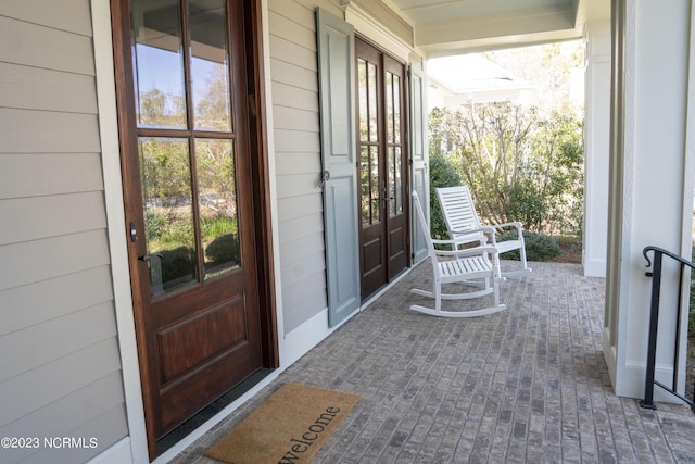 view of exterior entry with french doors and a porch