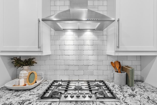 2900 Legends Dr, Southport, NC 28461 - kitchen featuring wall chimney exhaust hood, stainless steel gas stovetop, backsplash, and white cabinetry