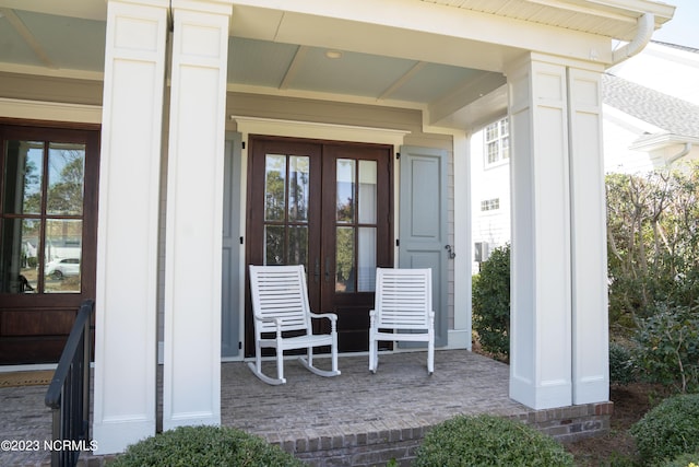 property entrance with covered porch and french doors