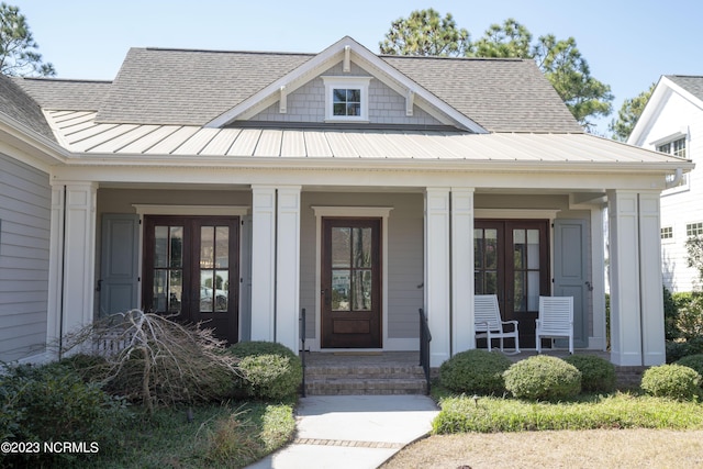 property entrance with metal roof, covered porch, french doors, roof with shingles, and a standing seam roof