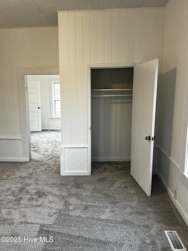 unfurnished bedroom featuring carpet, a closet, visible vents, and wooden ceiling