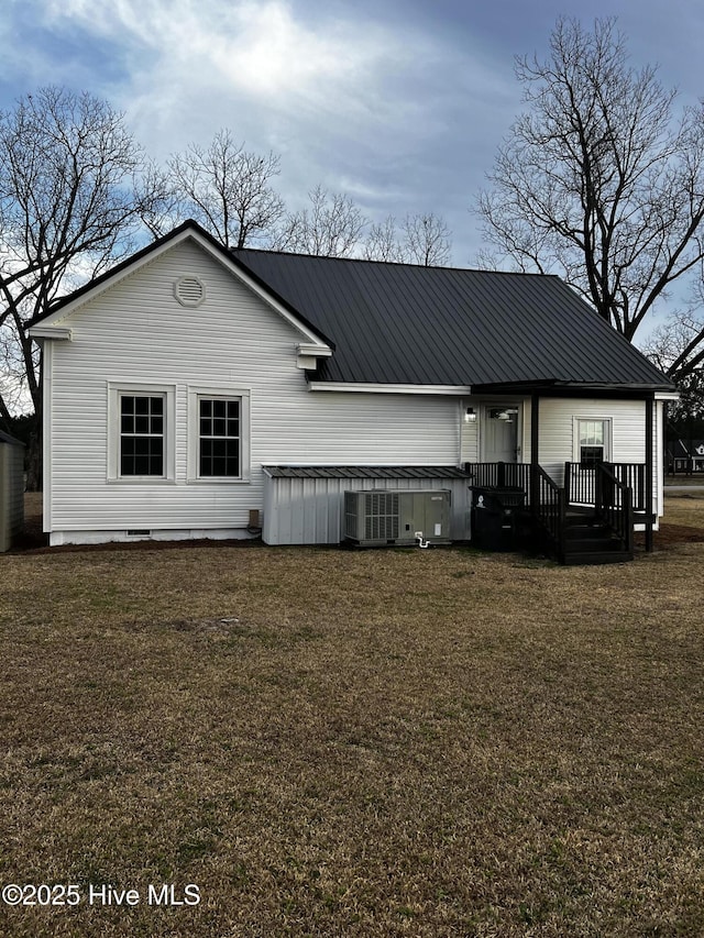 rear view of property with metal roof and a lawn