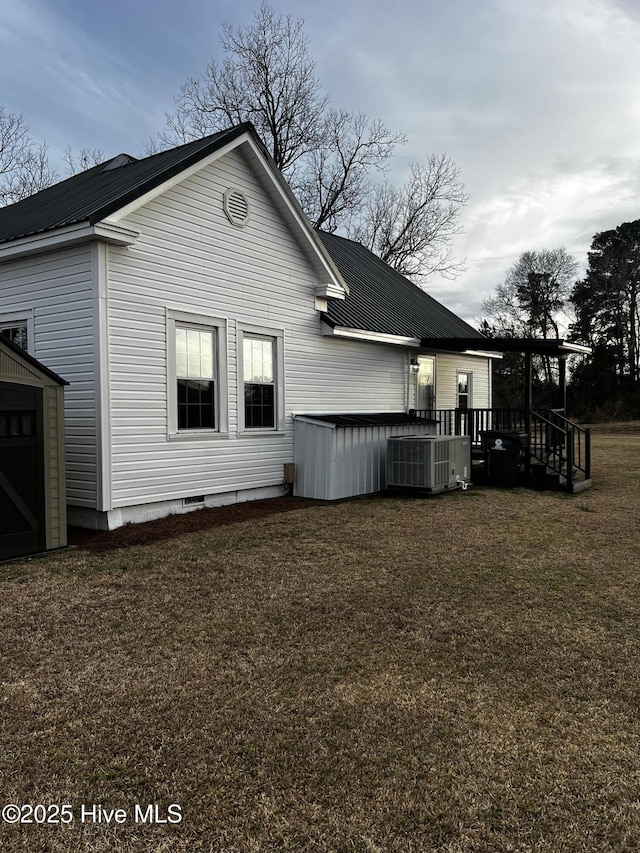 back of property with cooling unit, metal roof, a deck, and a lawn