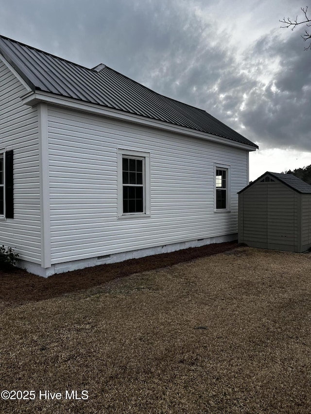 view of home's exterior featuring crawl space, a standing seam roof, metal roof, a shed, and an outdoor structure