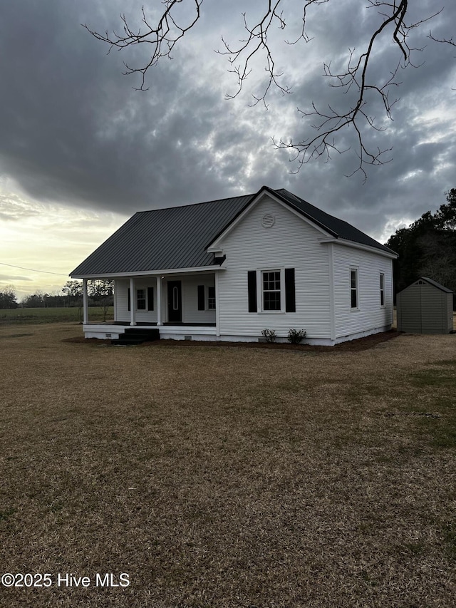 view of front of home with covered porch, metal roof, and a front lawn