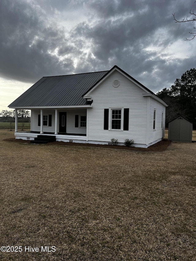 view of front facade with covered porch, metal roof, and a front yard