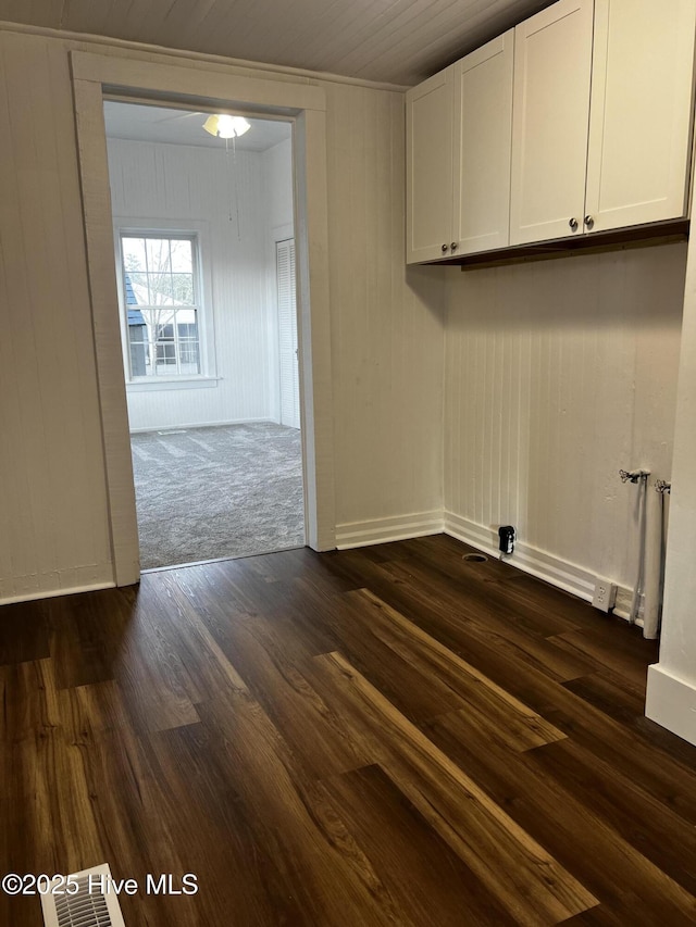 laundry area featuring cabinet space, baseboards, and dark wood-style floors