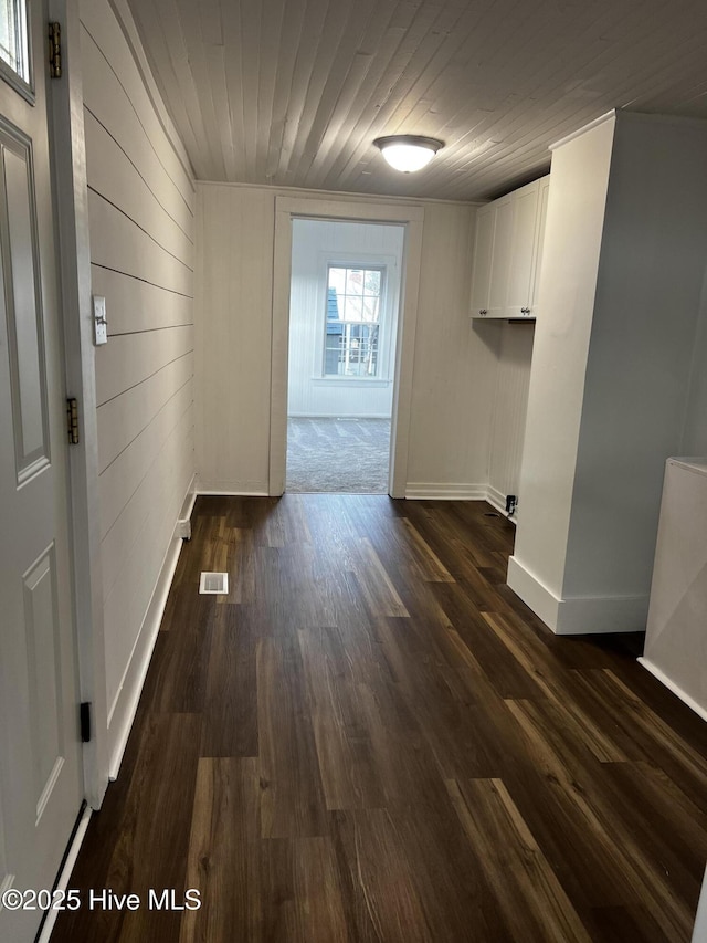 hallway featuring dark wood-style floors, wood ceiling, visible vents, and baseboards