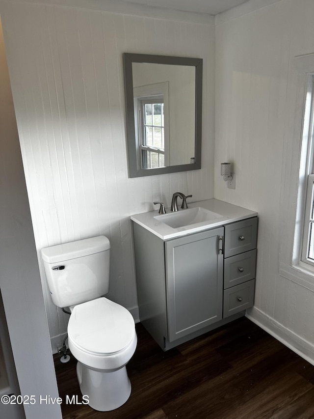 half bathroom featuring toilet, wood finished floors, and vanity