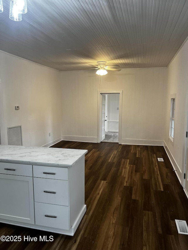 empty room featuring dark wood-style flooring, visible vents, ceiling fan, and baseboards