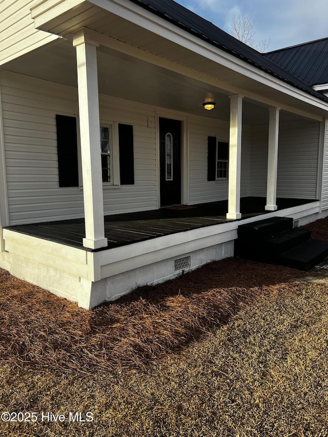 doorway to property with crawl space, a porch, and metal roof